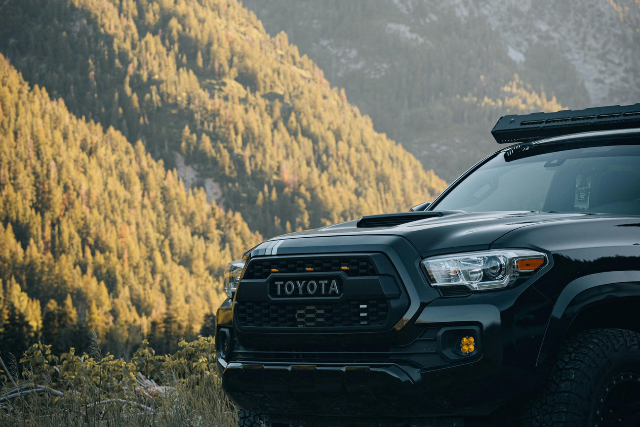 Black Toyota truck front with rugged grille in mountain landscape, LynXautoinnovate USA automotive parts