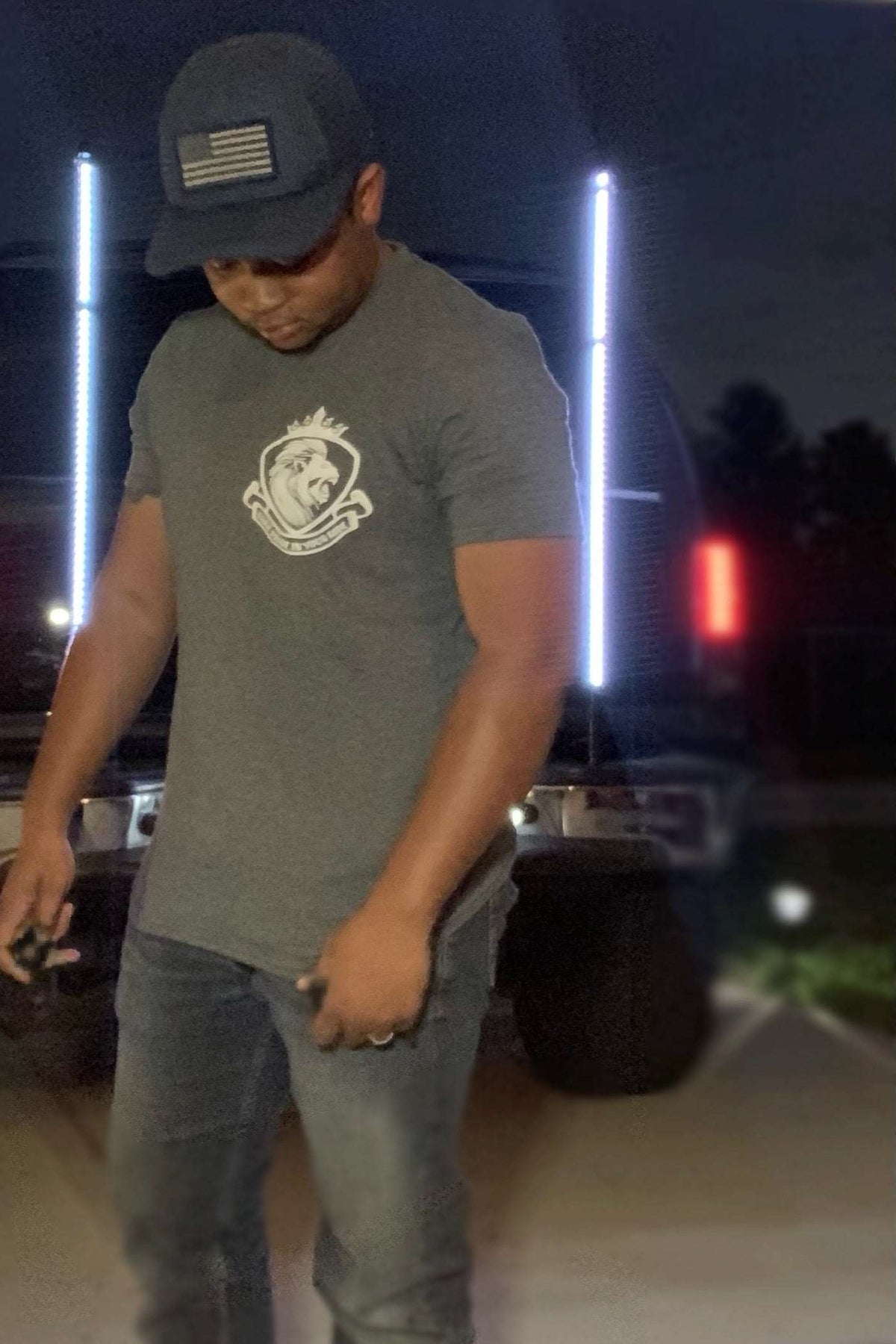Man in LynXautoinnovate classic grey t-shirt by a truck at night, automotive apparel style